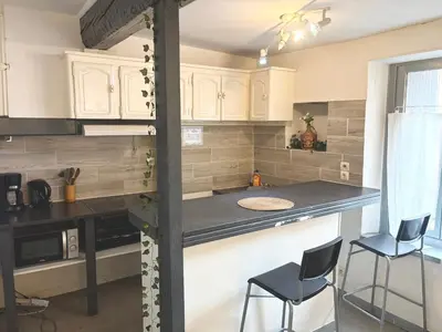 a kitchen with white cabinets and a counter with two chairs at Appartement 2 Chambres in Carcassonne