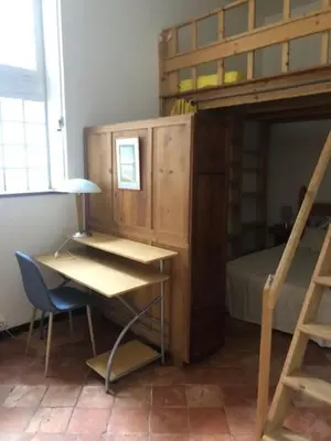 a bedroom with a desk and a bunk bed at Tranquille et chaleureux in Carcassonne