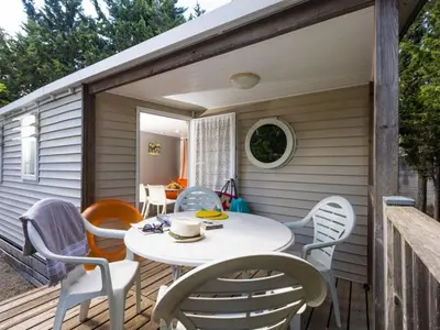 a patio with a table and chairs on a deck at Mobil-home confortable avec terrasse - API-1-52-652 in Lézignan-Corbières