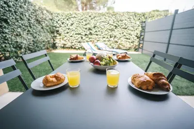 a table with plates of food and glasses of orange juice at Parking Sécurisé -Climatisé-Piscine-Terrasse-AM in Carcassonne