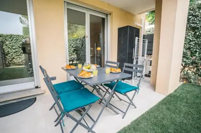 a table and chairs on a patio with food on it at Parking Sécurisé -Climatisé-Piscine-Terrasse-AM in Carcassonne