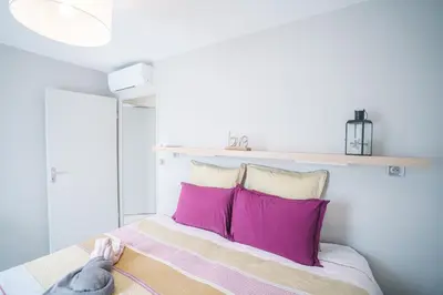 a bedroom with a bed with pink pillows at Parking Sécurisé -Climatisé-Piscine-Terrasse-AM in Carcassonne