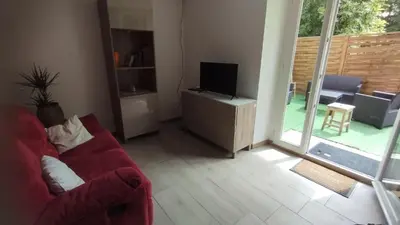 a living room with a red couch and a television at Gite de l'abreuvoir in Saint-Gaudéric
