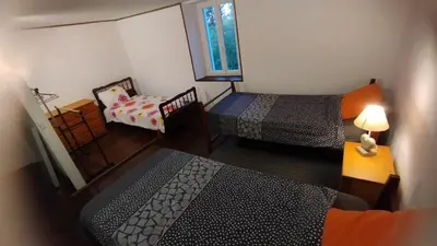 a room with two beds and a chair and a window at Gite de l'abreuvoir in Saint-Gaudéric