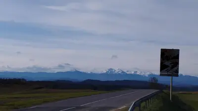 a road with a sign and mountains in the background at Gite de l'abreuvoir in Saint-Gaudéric