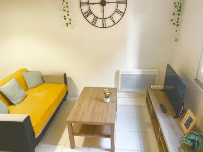 a living room with a couch and a table and a clock at Appartement Du DONJON in Carcassonne