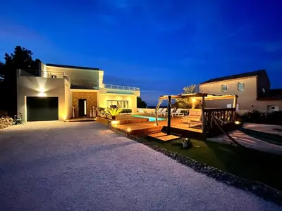 a house with a pool in the yard at night at Modern villa with sea view in Fitou
