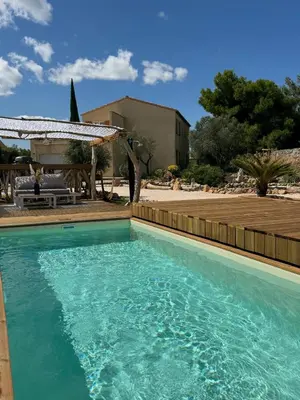 a swimming pool with blue water in a yard at Modern villa with sea view in Fitou