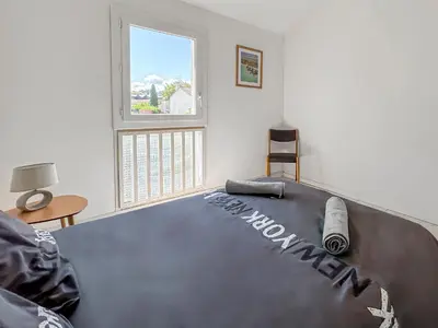 a bedroom with a large bed in a room with a window at Maison avec Jardin, Terrasse, cheminée insert et bois in Carcassonne