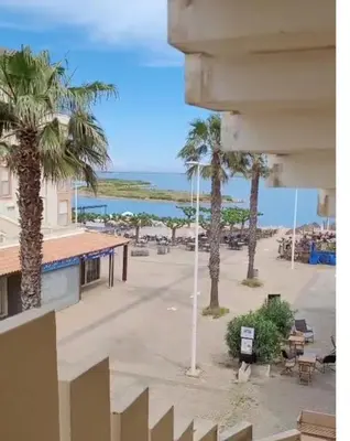 a view of the beach from a building with palm trees at Le Thalassa II in Gruissan