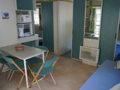 a room with a table and chairs and a kitchen at Chalet confortable avec terrasse à Sournia - API-1-52-491 in Sournia