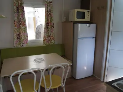a small kitchen with a table and a refrigerator at Mobil-home confortable avec terrasse pour 4 personnes à Sournia - API-1-52-622 in Sournia