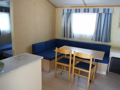 a small room with a table and chairs and a couch at Mobil-home avec Terrasse Accueillant 6 Pers - API-1-52-631 in Sournia
