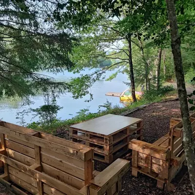 a picnic table and benches next to a lake at Chalet atypique in Anglès