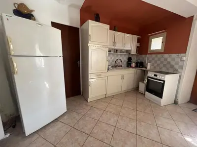 a kitchen with white cabinets and a white refrigerator at Charmante maison de village à Tourouzelle in Tourouzelle