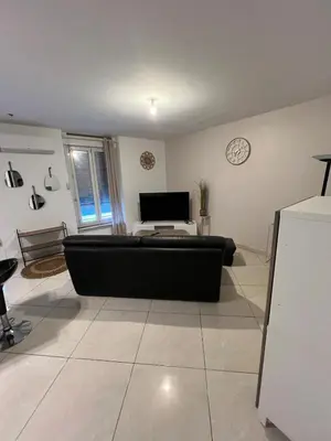 a living room with a black couch and a clock at T2 apartment, terrasse cours intérieur in Narbonne