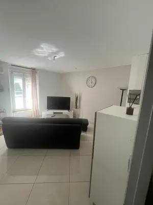 a living room with a black couch and a television at T2 apartment, terrasse cours intérieur in Narbonne