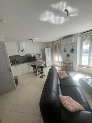 a living room with a black couch and a kitchen at T2 apartment, terrasse cours intérieur in Narbonne