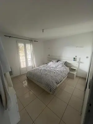 a white bedroom with a bed and a window at T2 apartment, terrasse cours intérieur in Narbonne