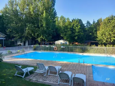 a swimming pool with four chairs and a group at Mobil Home La Belle Vie in Vaudreuille