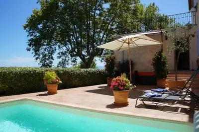 a pool with an umbrella and a chair and a table at Chambre des Remparts in Lautrec