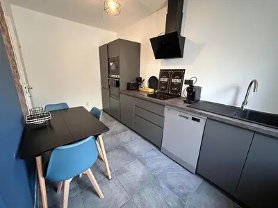 a kitchen with a table and blue chairs in it at Appartement au calme commerces à proximité in Castres