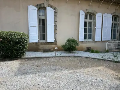 a building with white shuttered windows and a bush at Appartement au calme commerces à proximité in Castres