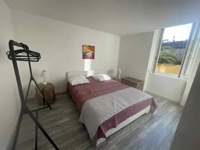 a bedroom with a bed and a large window at Le Nid du Peintre in Narbonne