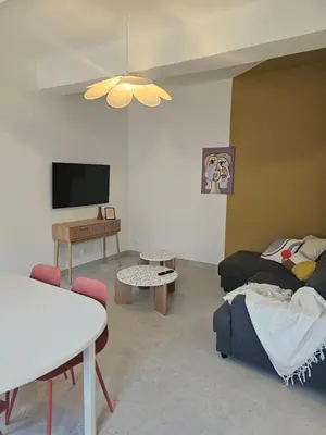 a living room with a couch and a tv at Les Oreillers Multicolores in Castelnau-dʼAude