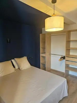 a bedroom with a white bed and a blue wall at Les Oreillers Multicolores in Castelnau-dʼAude