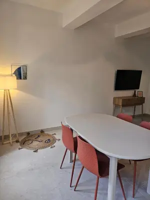 a white table and chairs in a room with a tv at Les Oreillers Multicolores in Castelnau-dʼAude