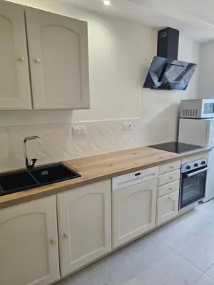 a kitchen with white cabinets and a sink at Les Oreillers Multicolores in Castelnau-dʼAude
