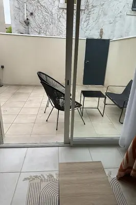 a room with a chair and a table on a tile floor at Le Riquet Duplex neuf climatisé au calme in Carcassonne