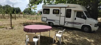 a table and chairs in front of a van at Le camping-car de la Gardié in Vielmur-sur-Agout