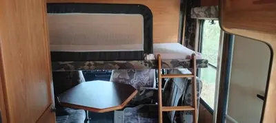 a small room with a bunk bed and a table at Le camping-car de la Gardié in Vielmur-sur-Agout
