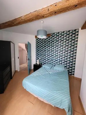 a bedroom with a bed with a blue comforter at Maison de village Olonzac in Olonzac