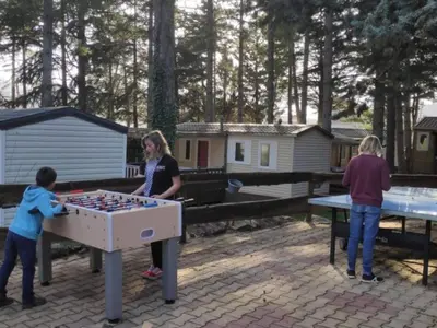a woman and two children playing with a table football at Mobil-home spacieux avec terrasse - 6 personnes - API-1-52-676 in Sournia