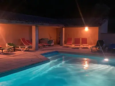 a swimming pool at night with chairs and a couch at Belle vue avec piscine sécurisée in Sainte-Camelle