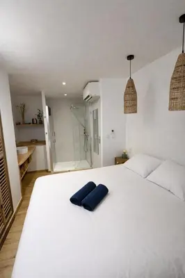 a bedroom with a white bed with a blue pillow on it at Charmante maison rénovée au cœur du village de Gruissan in Gruissan