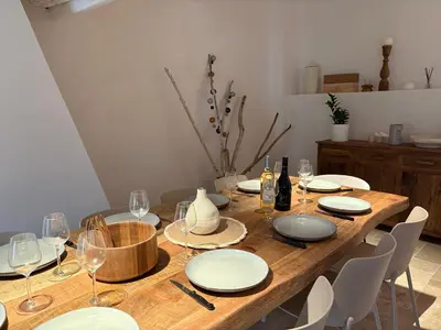 a wooden table with white plates and wine glasses at Charmante maison rénovée au cœur du village de Gruissan in Gruissan