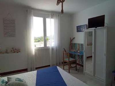 a bedroom with a bed and a window and a table at Chambre la plage in Limoux
