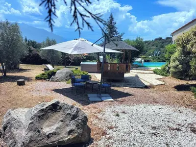 a patio with a table and an umbrella next to a pool at Entre mer et montagnes in Arboussols