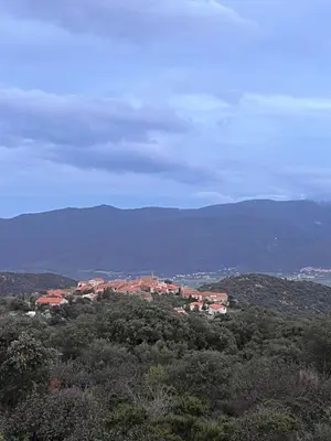 a town on a hill with mountains in the background at Entre mer et montagnes in Arboussols
