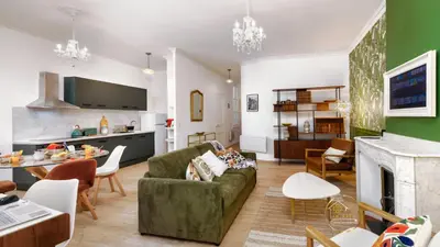 a living room with a green couch and a kitchen at Heart of Oc Mistral Elegant & Spacious Center Train Station in Narbonne