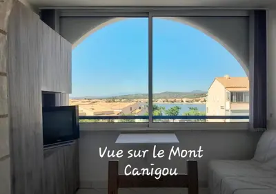 a room with a large window with a couch and a tv at Petit appartement entre mer et montagne in Port-la-Nouvelle