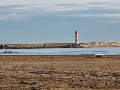 a lighthouse sitting on the beach with the ocean at Petit appartement entre mer et montagne in Port-la-Nouvelle