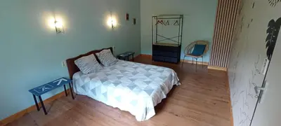 a bedroom with a bed and a table and a chair at Chambres d'hôtes Las Carbounieros