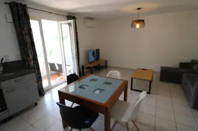 a living room with a table and chairs and a couch at Villa l'Oranger in Sigean