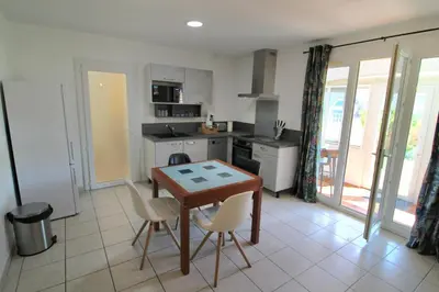 a kitchen with a wooden table and chairs in it at Villa l'Oranger in Sigean