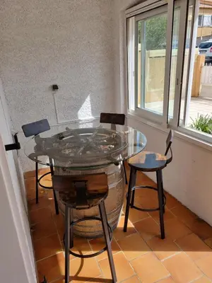 a glass table and chairs in a room with a window at Villa l'Oranger in Sigean